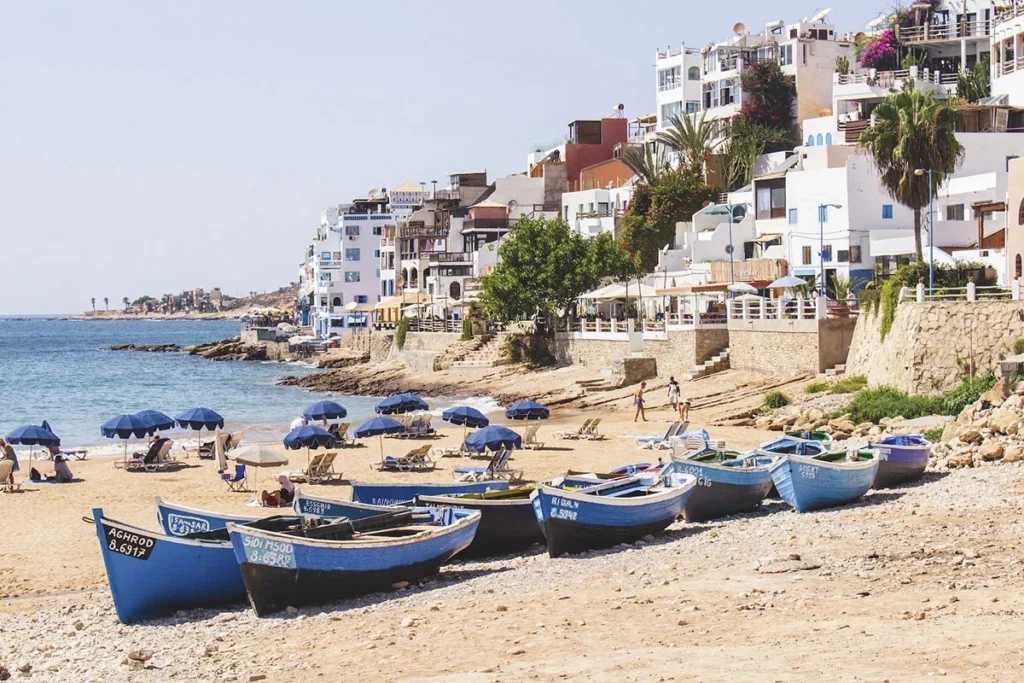 Sunny day at Taghazout beach featuring traditional blue boats, located north of Agadir.