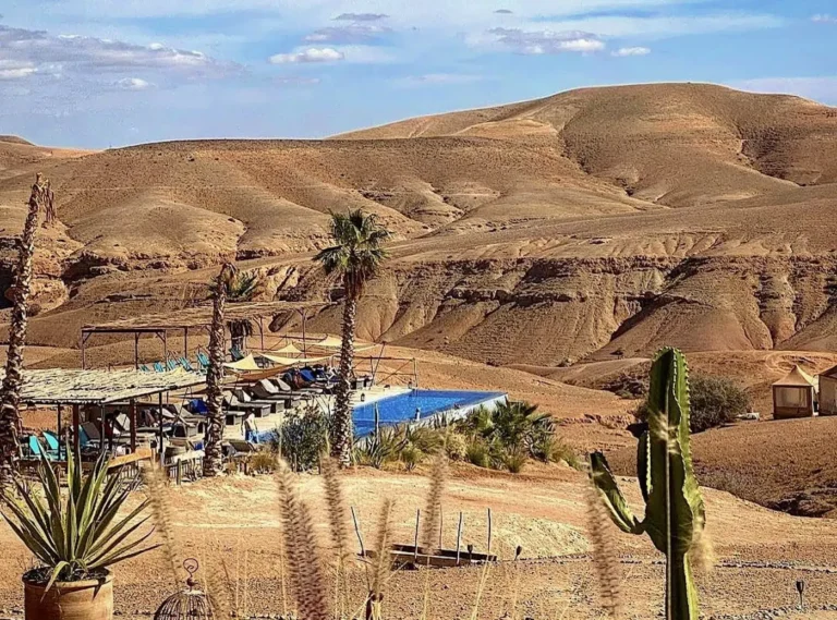 Breathtaking sunset view over the rocky Agafay desert with luxury camps and Atlas Mountains.
