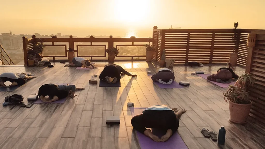 Rooftop sunset yoga session in a Tamraght surf house.